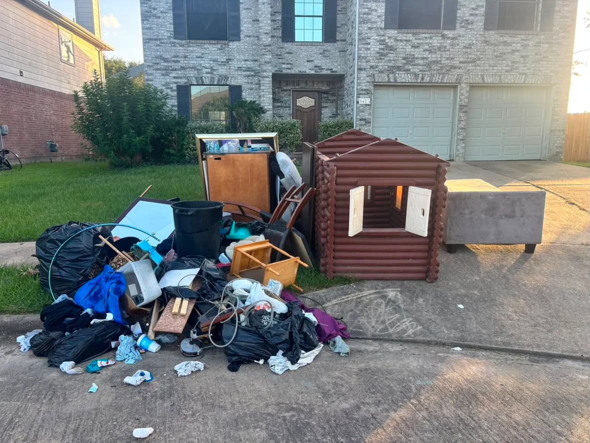 Furniture, bags, and household junk along a driveway before a 005 pickup